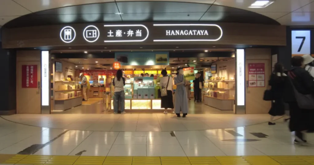 駅構内の土産・弁当専門店「HANAGATAYA」の店舗外観と商品を選ぶ人々
