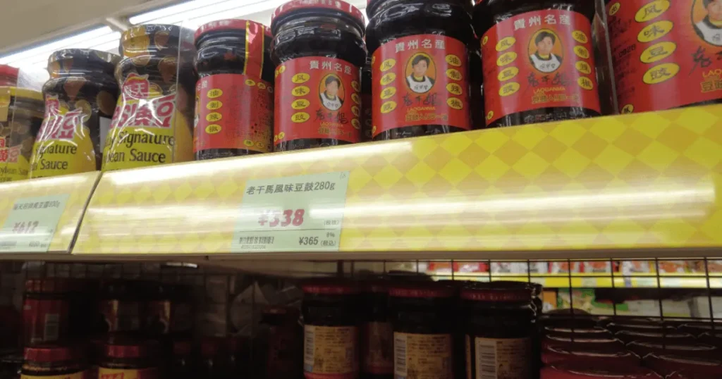 中華食材売り場に並ぶ老干媽(ラオガンマ)風味豆豉280g瓶と338円の価格表示POP